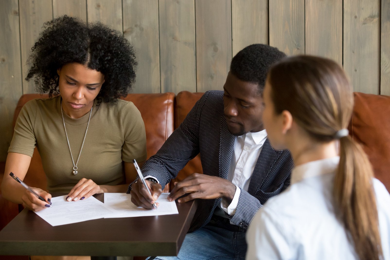 Black couple closing deal by signing contract in cafe